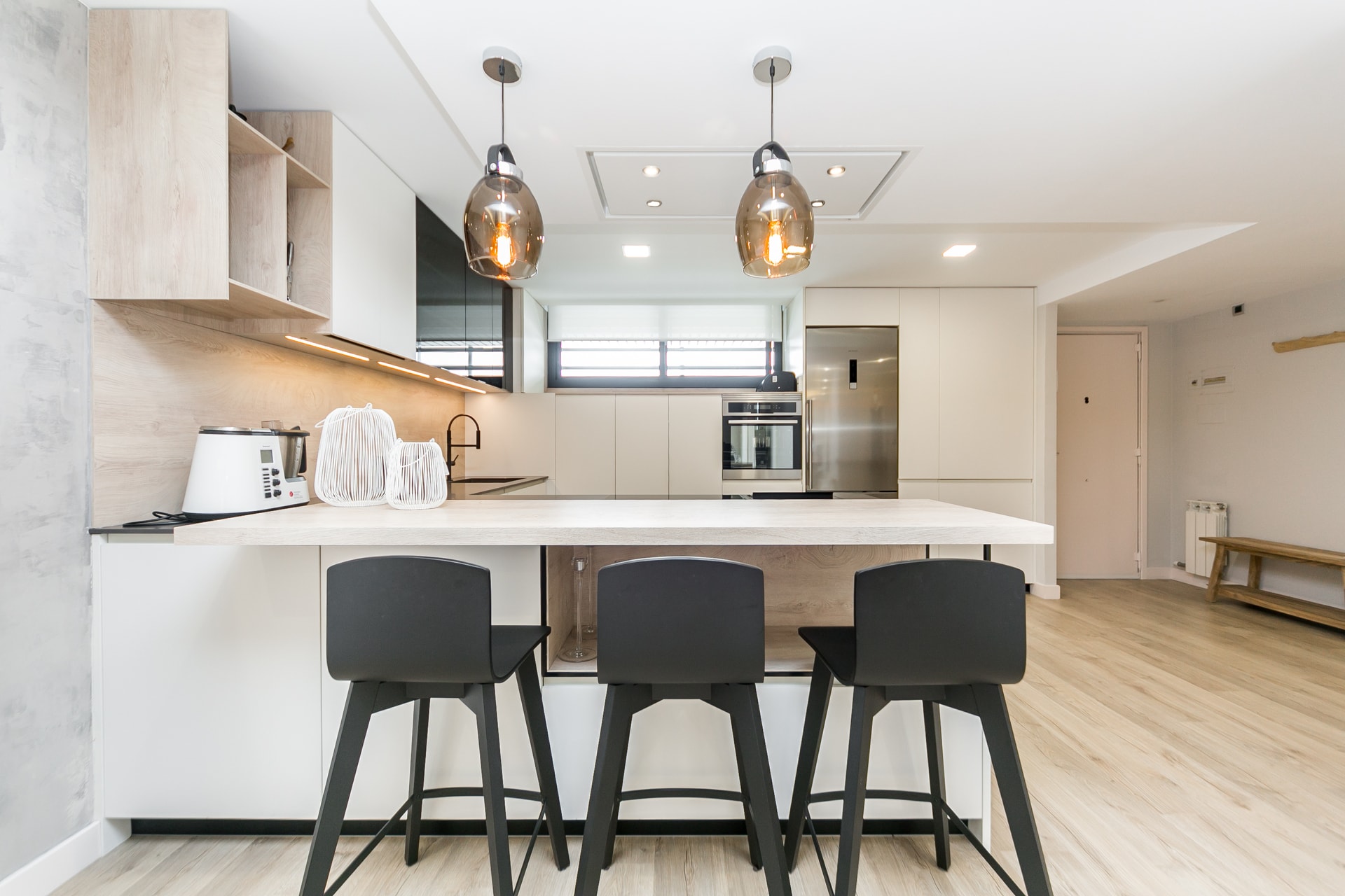 Cocina abierta al salón con barra y taburetes